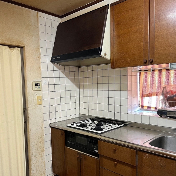 交換工事前の古いガスコンロとレンジフードの写真